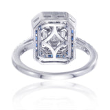 Angle view of baguette illusion diamond ring with invisible set blue sapphire halo in white gold
