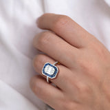 Blue sapphire halo ring worn on hand showing deep blue sapphire invisible setting around illusion diamond centre